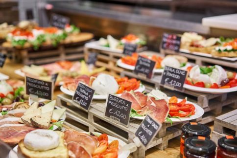 Deli plates on display with various meats and vegetables for sale