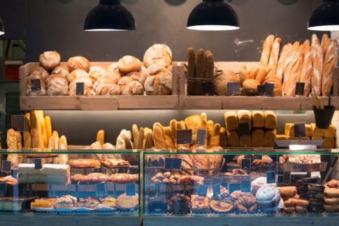 Bakery counter containing various baked goods suck as loaves of bread, cakes, and donuts